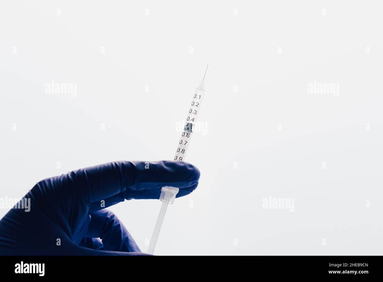 Hand with gloves holding injection. Health medical attention. Background epidemic situation with copy space. Stock Photo
