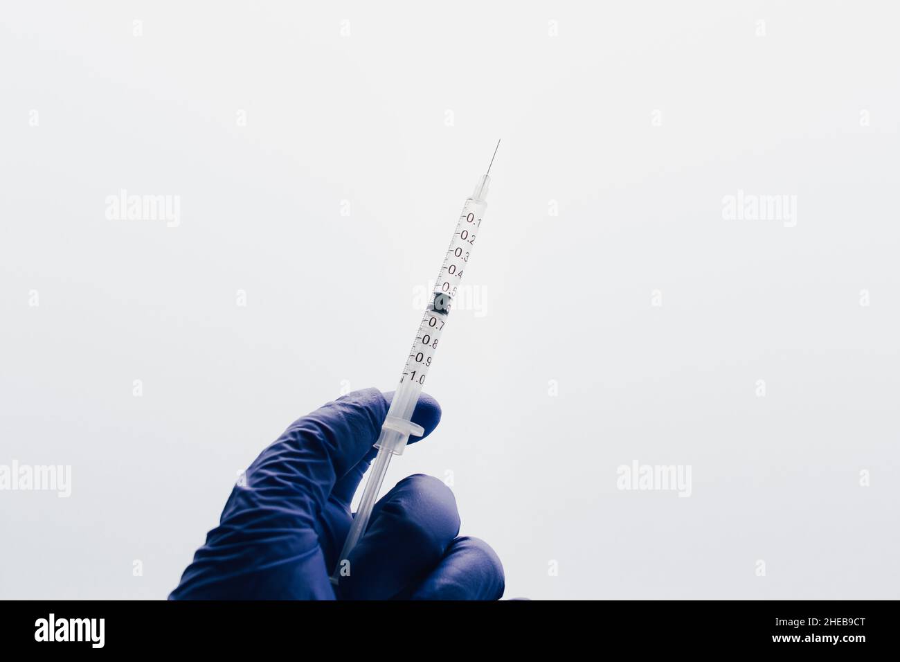 Hand with gloves holding injection. Health medical attention. Background epidemic situation with copy space. Stock Photo