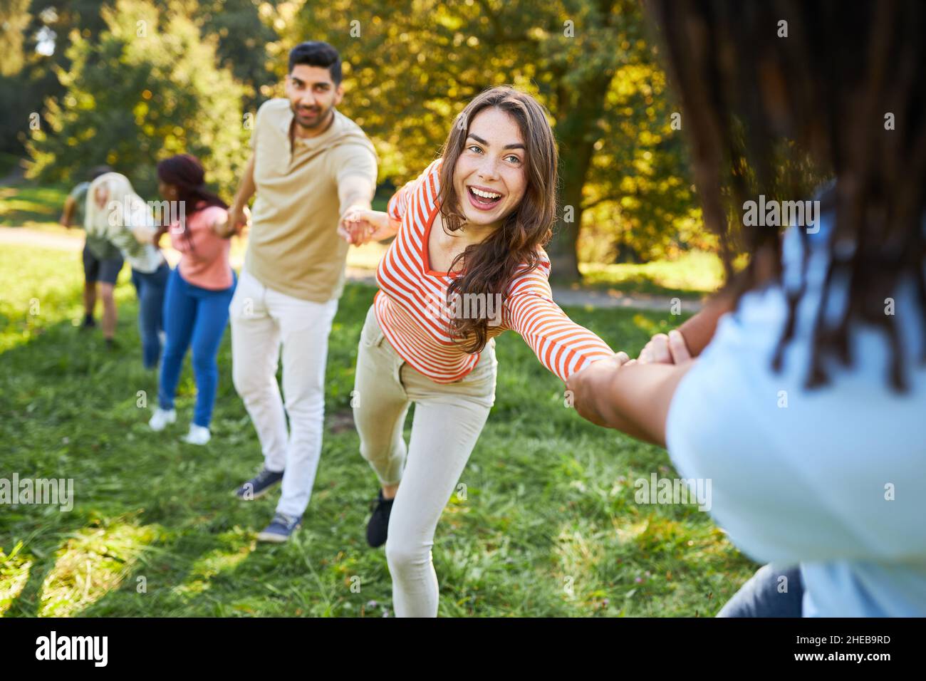 Young people stand hand in hand in a meadow during exercise for ...