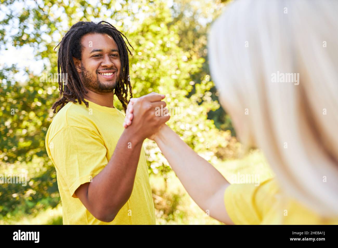 Two young people doing handshake as a greeting or as a team building exercise in summer Stock Photo