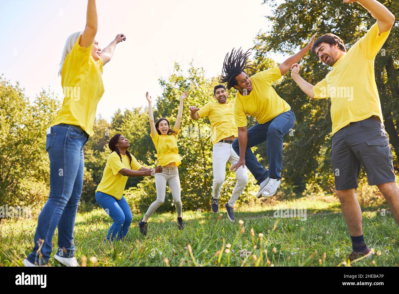Young people jump together in the air on a meadow for motivation and team building Stock Photo