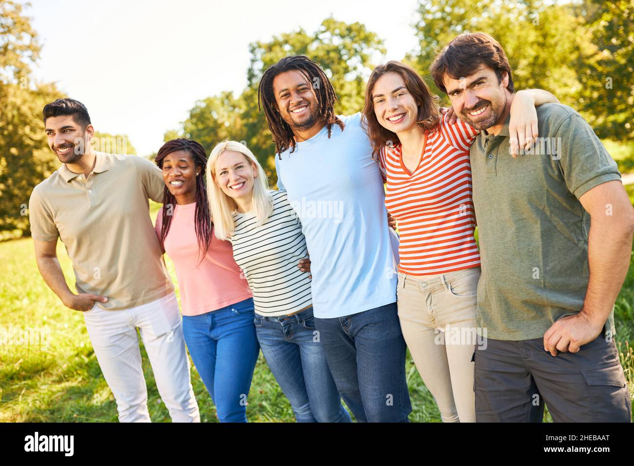Group of multicultural friends hug for diversity and inclusion in summer Stock Photo
