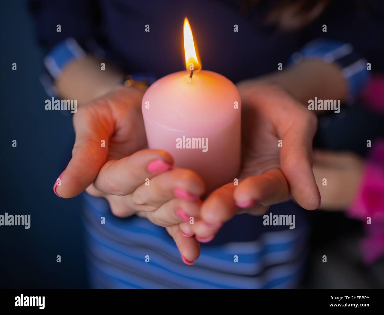 Closeup children's hands hold a candle in the church during prayer