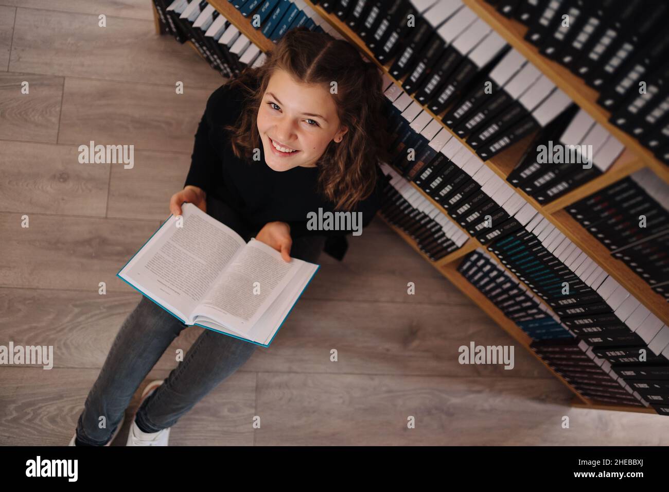 Teen girl among a pile of books. A young girl wearing glasses reads a ...