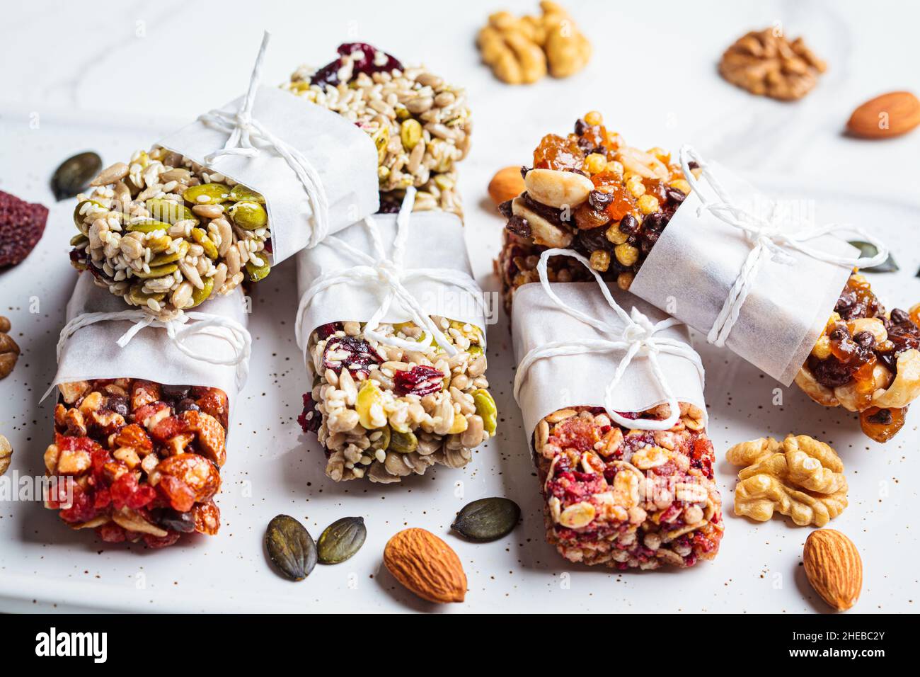 Energy granola bars with different seeds, nuts and dried fruits and berries on a white marble background. Healthy snack concept. Stock Photo