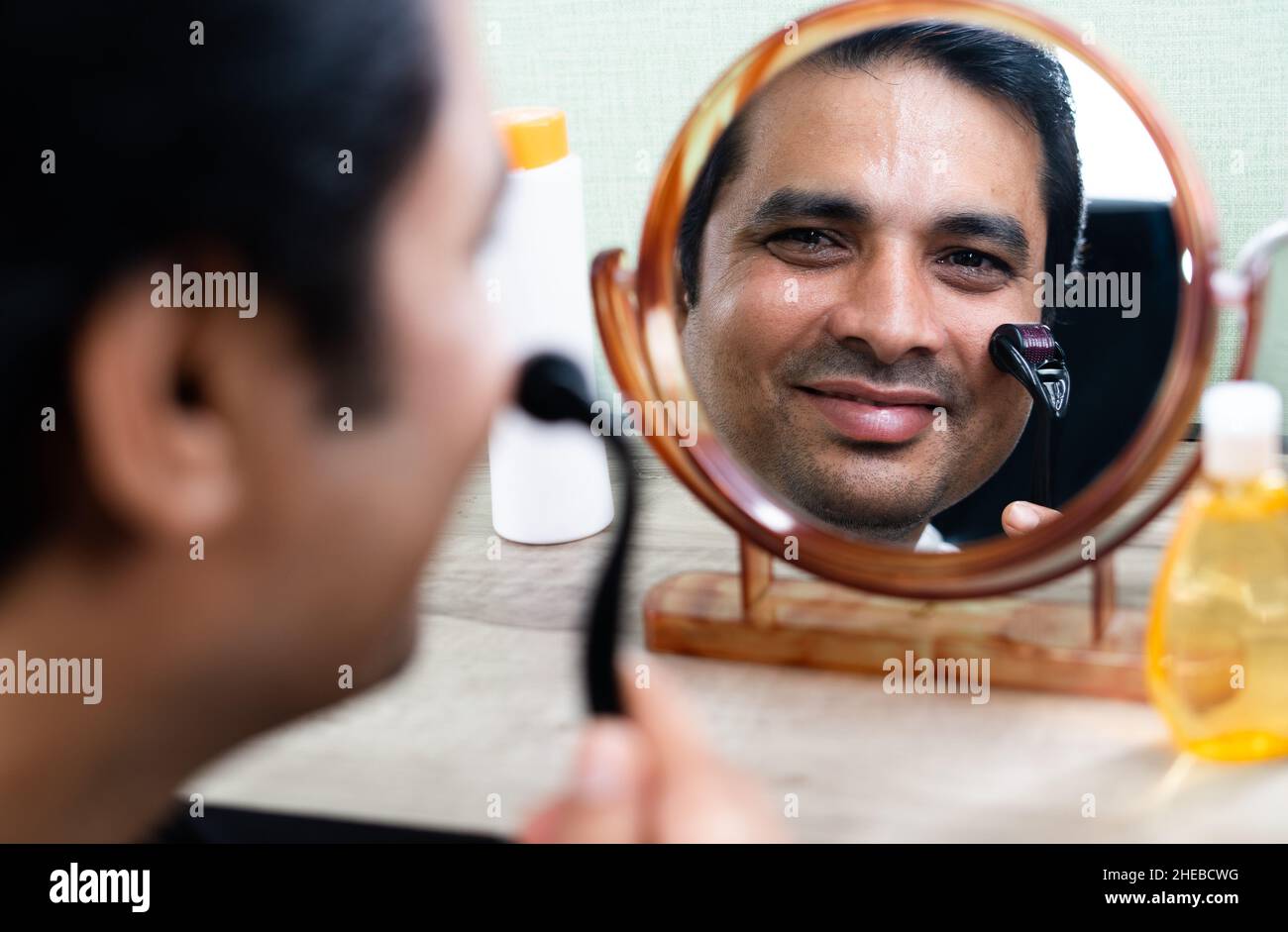 Handsome young Man using derma roller on face by looking