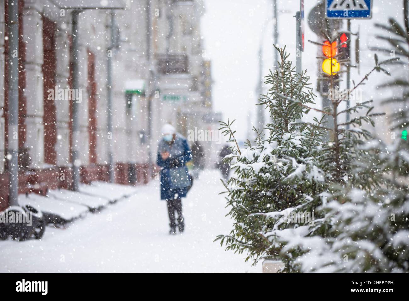 Snowfall on city streets. Blurred figure of a woman. that walks down the snowy street. Stock Photo