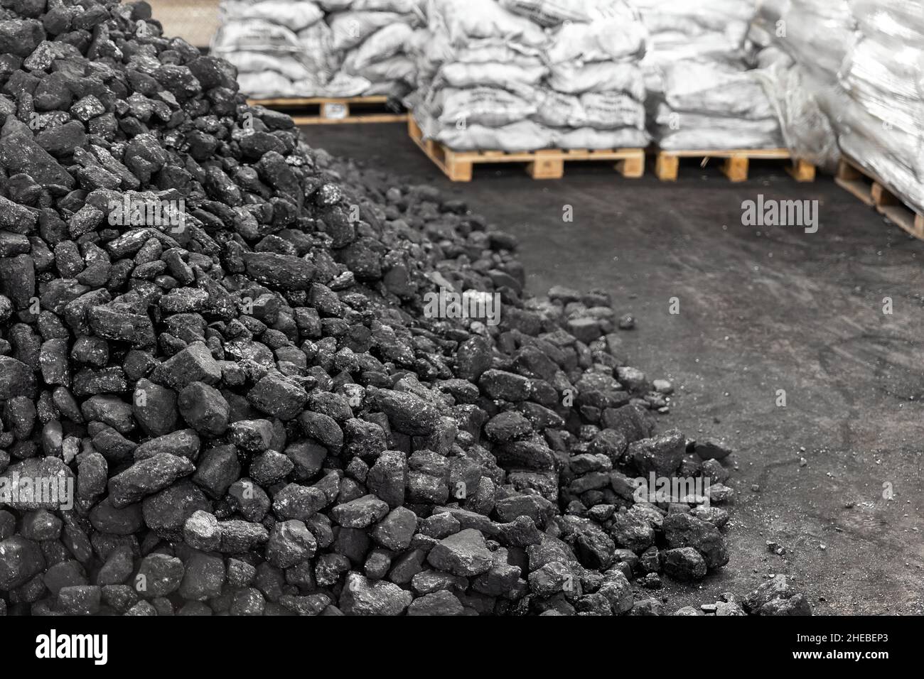 Big heap of dark black lump coal on floor bulk. Charcoal sorage at