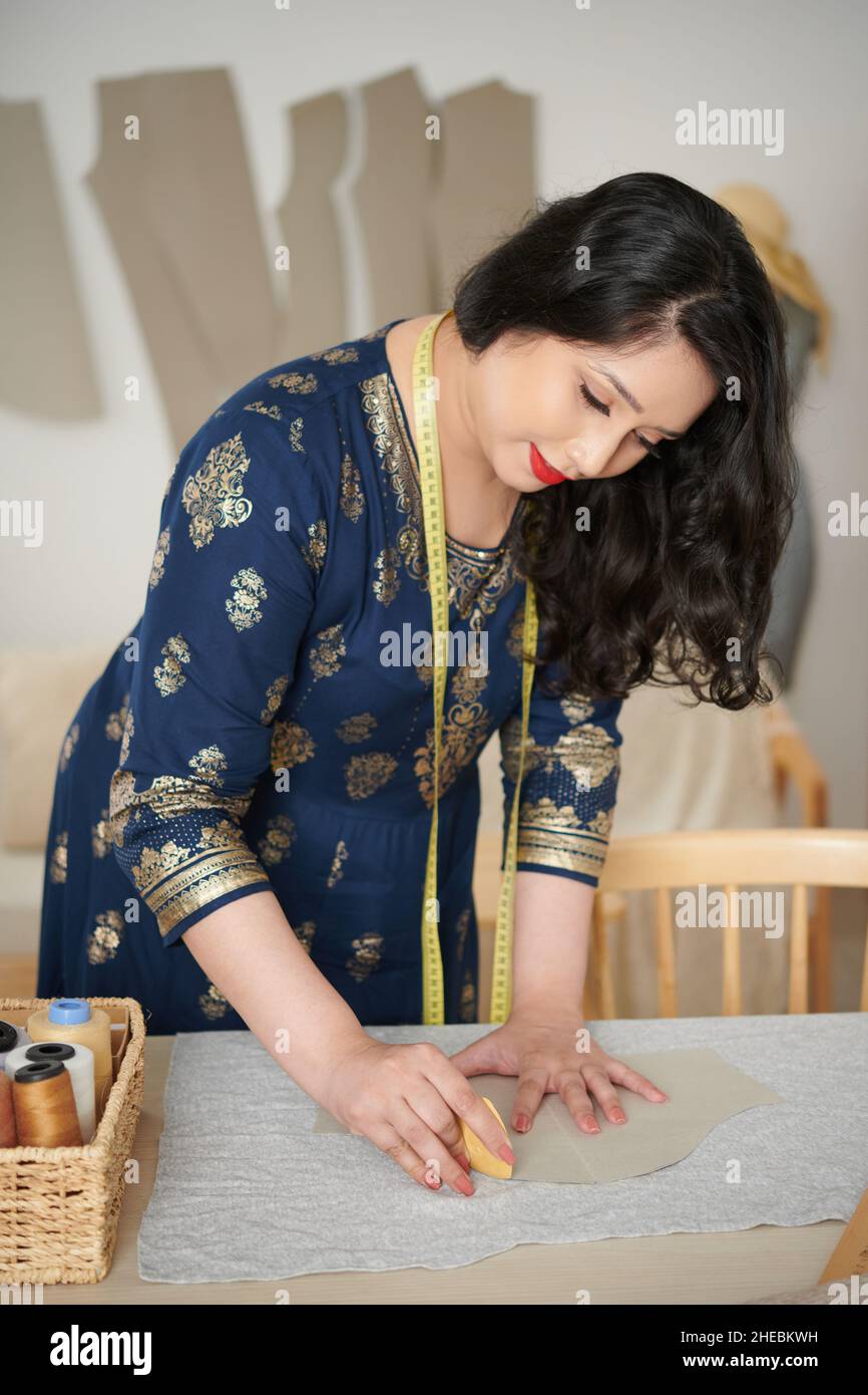 Dressmaker marking out sewing pattern of sleeve on fabric Stock Photo