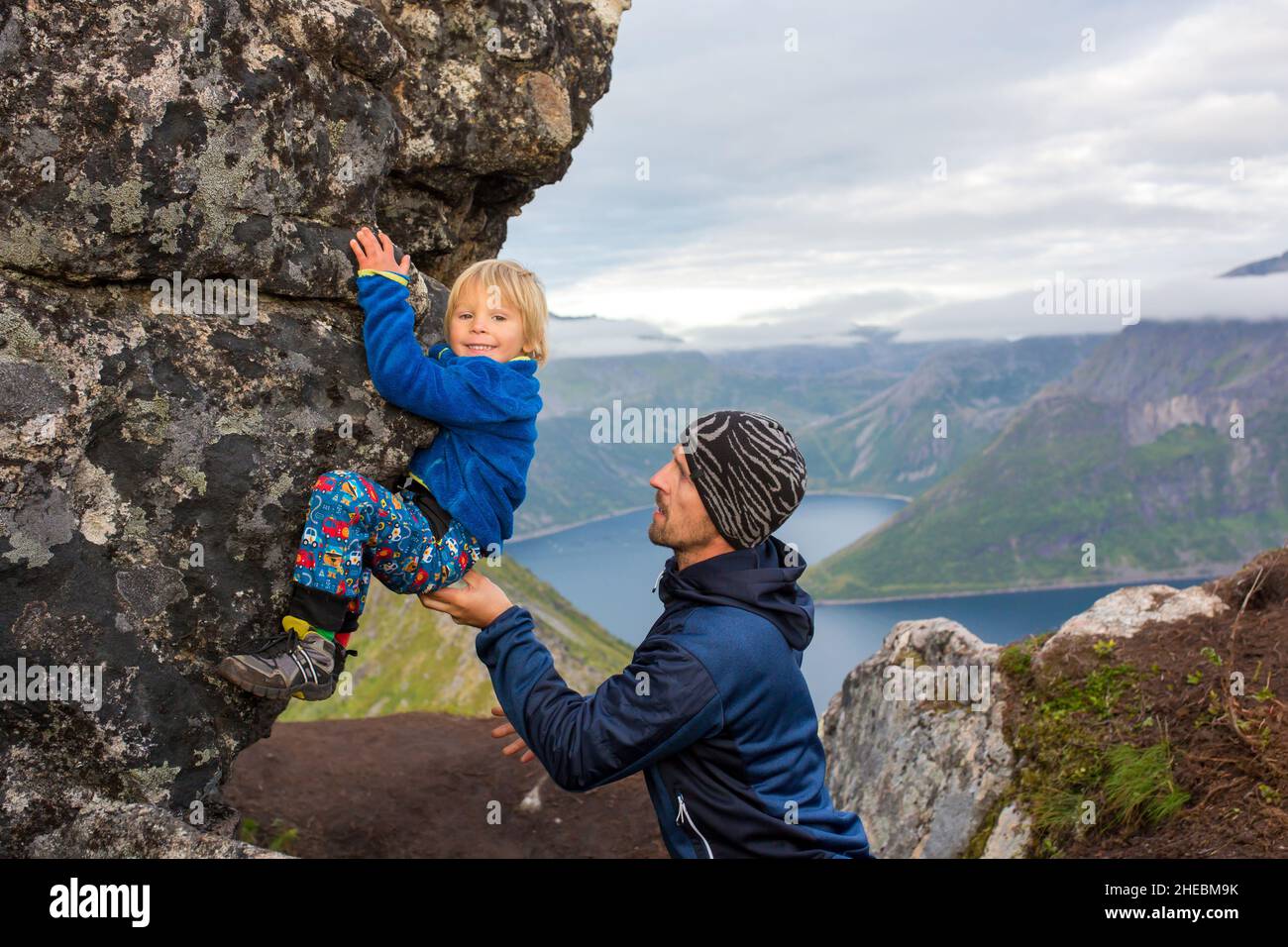 Happy child, hanging from a rock over Segla mountain on Senja island ...