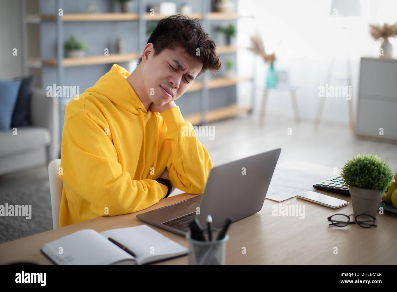 Stressed Asian male sitting at desk with pc Stock Photo