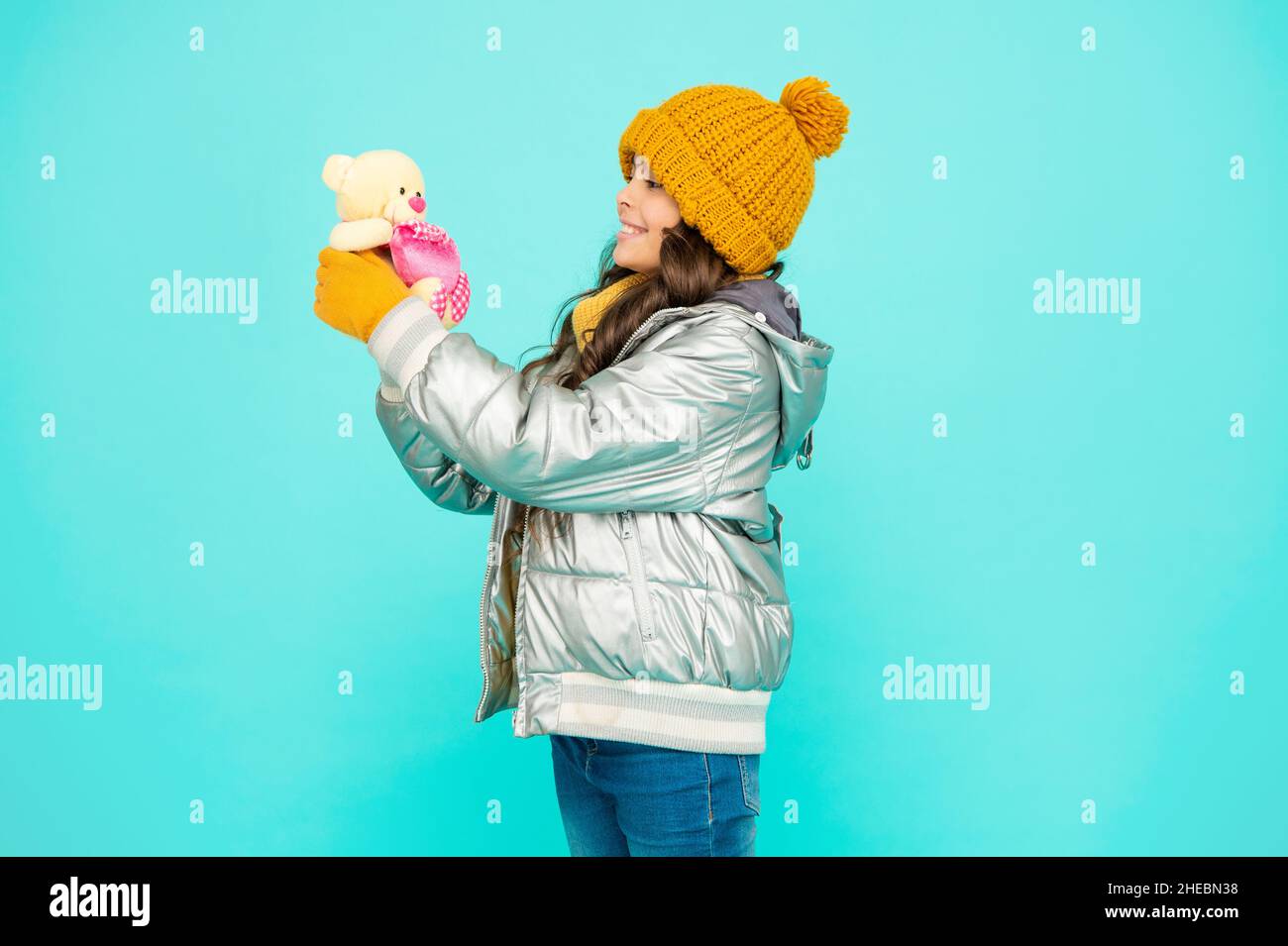 happy kid in hat and gloves hold toy on blue background, childhood Stock Photo