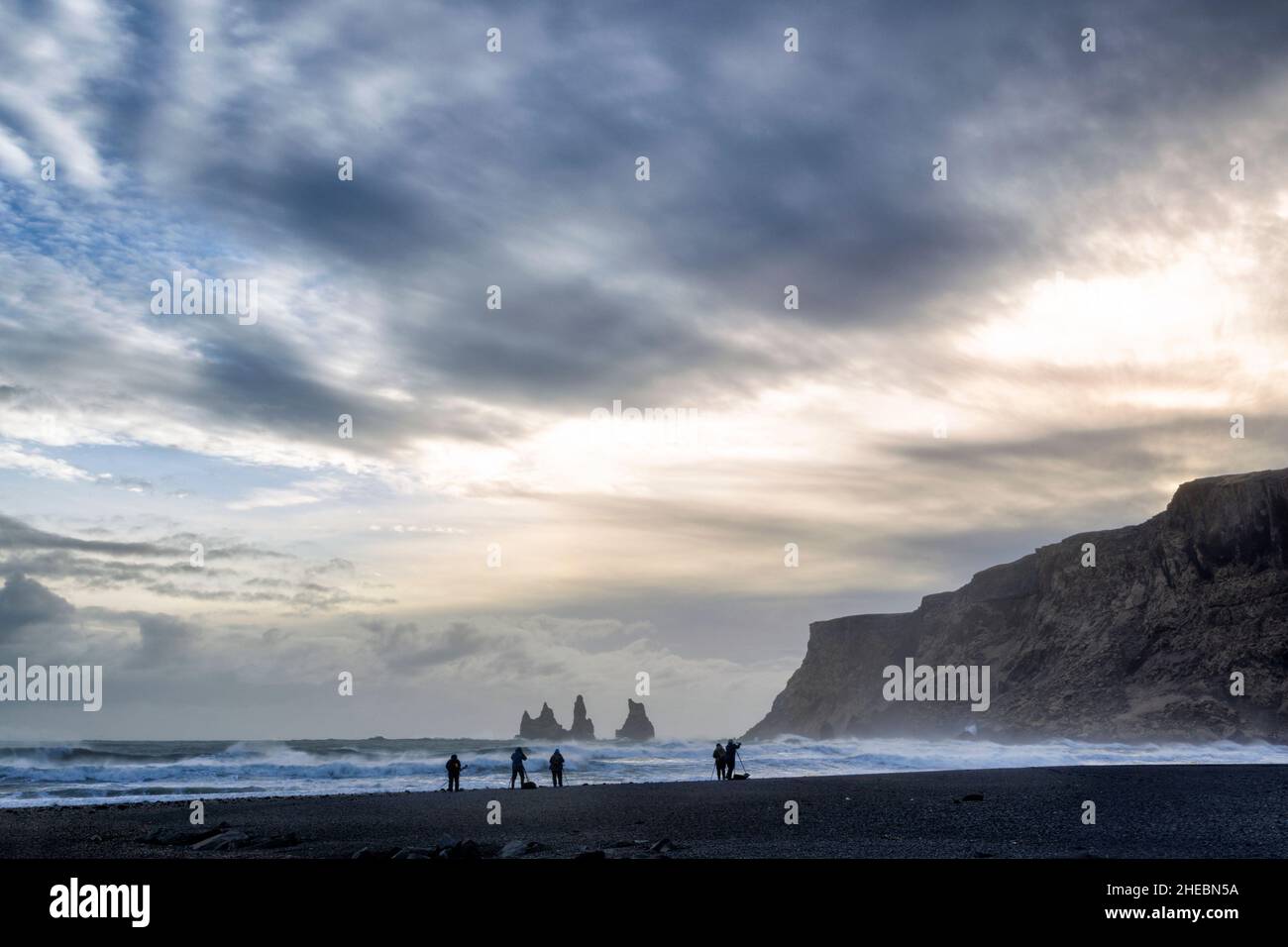 Photographers on the beach photograping rock stacks near to Vik in Iceland under a stormy sky and in front of a crashing waves Stock Photo
