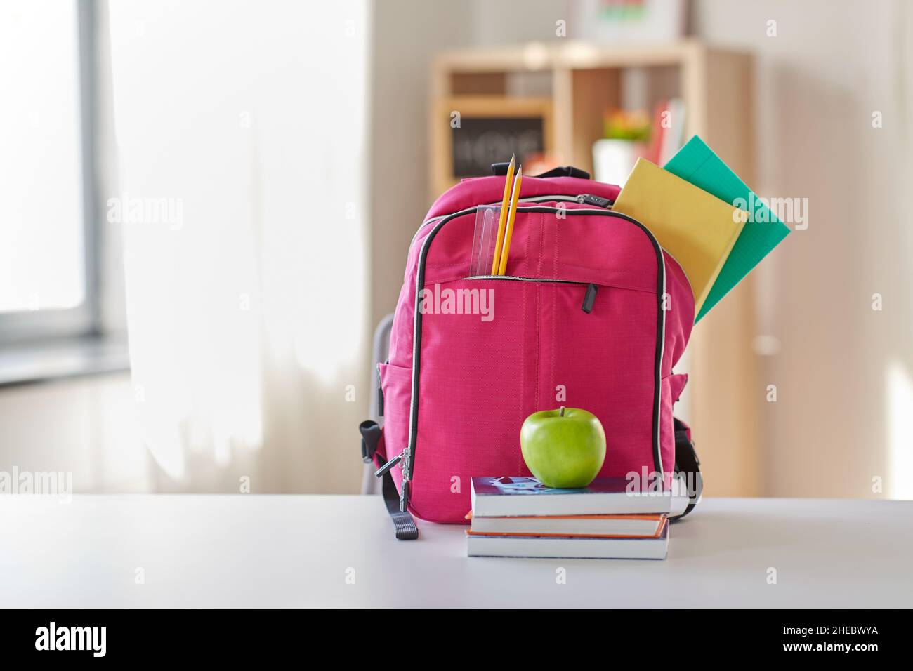 pink backpack, apple and school supplies on table Stock Photo