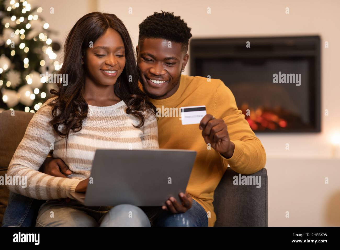 Spouses Shopping Via Laptop And Credit Card On Christmas Indoors Stock Photo
