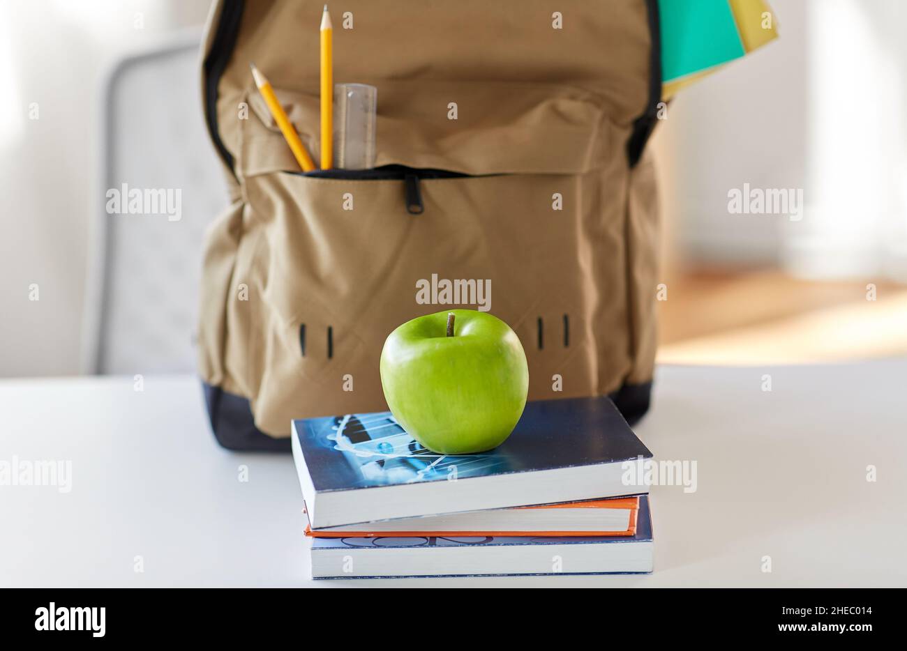 school backpack with books and apple on table Stock Photo
