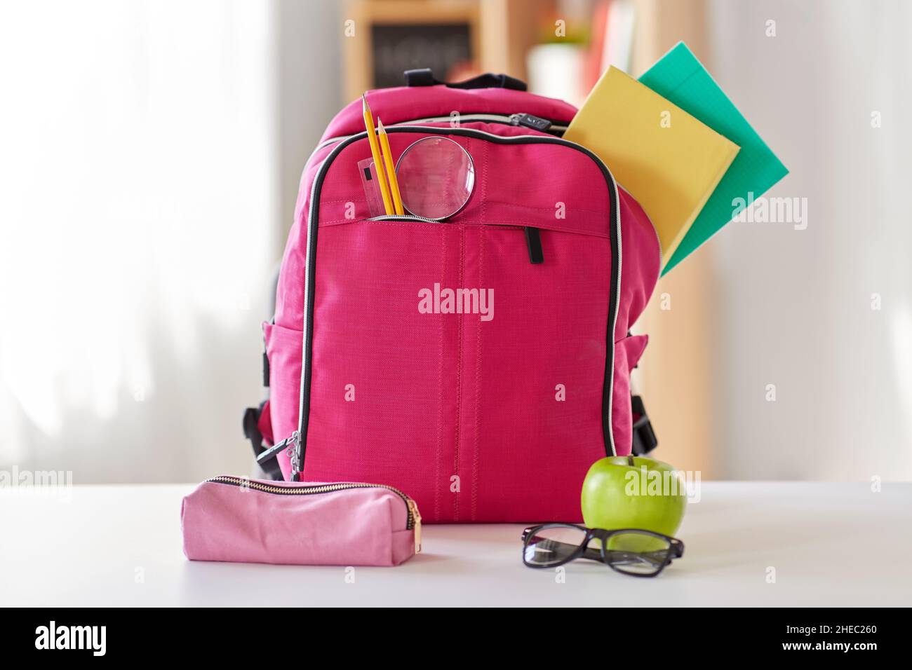 pink backpack, apple and school supplies on table Stock Photo