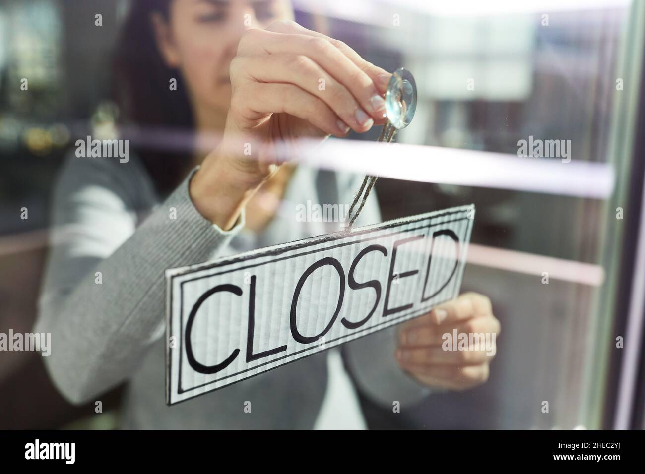 woman hanging banner with closed word on door Stock Photo