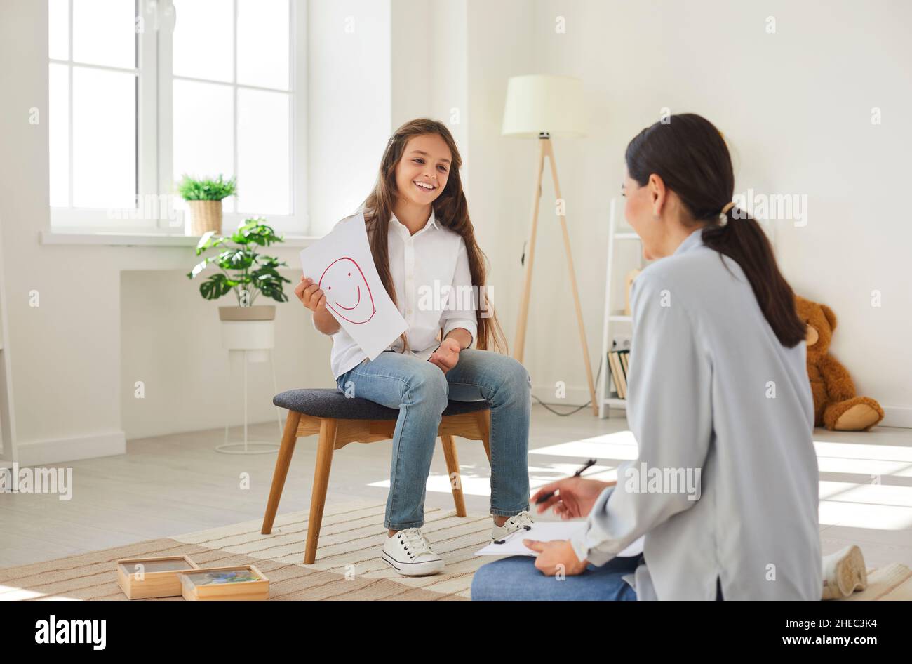 Happy teen girl in meeting with professional child psychologist talks about emotions. Stock Photo