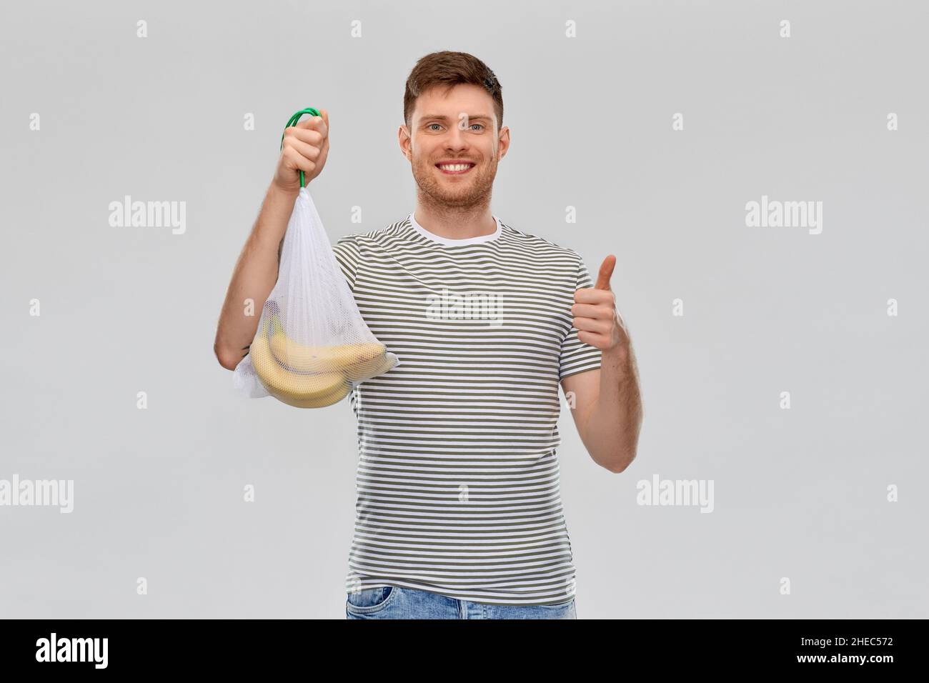 happy man holding reusable string bag with bananas Stock Photo