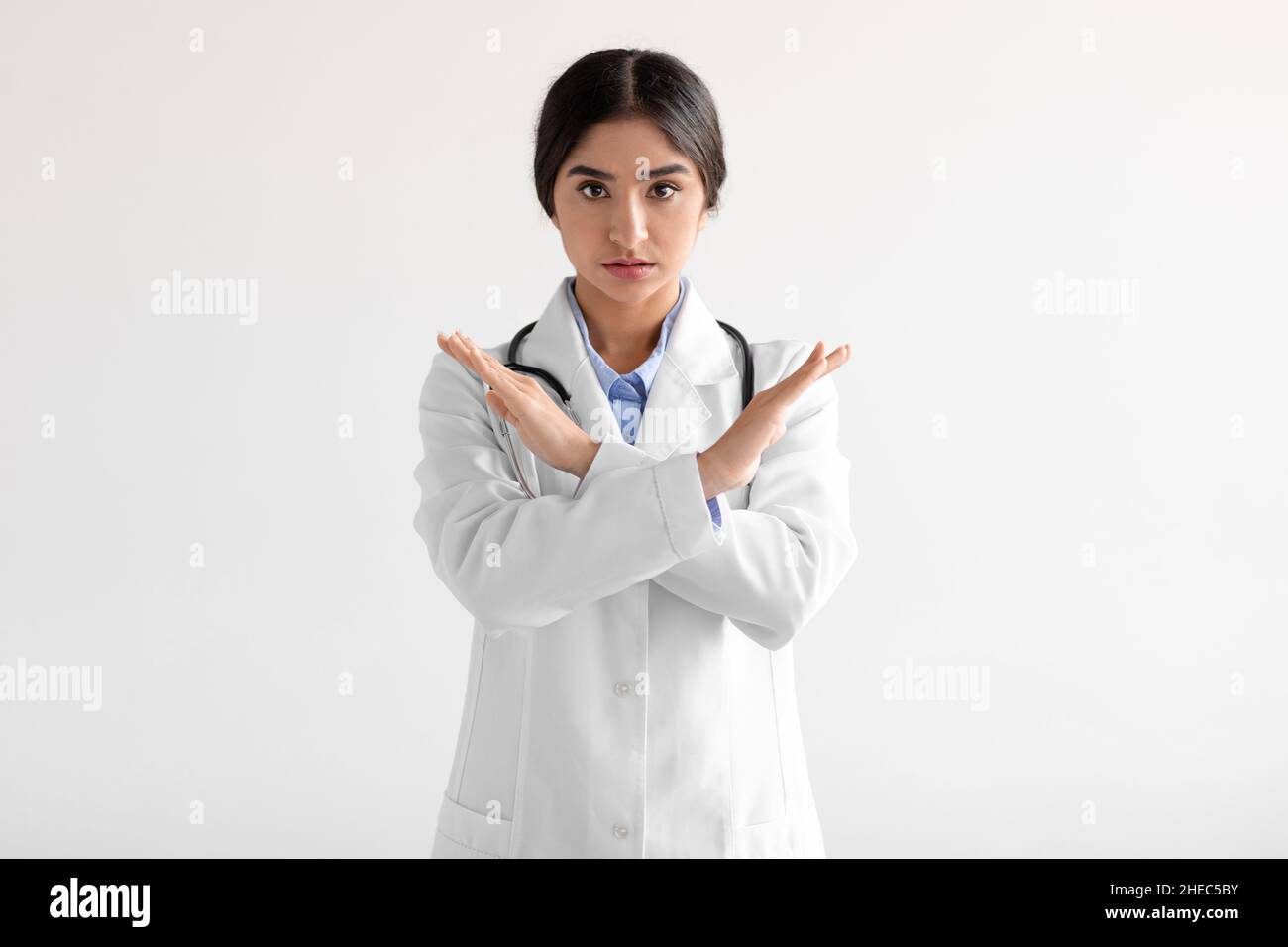Unhappy millennial cute hindu female medical worker in uniform say no, cross arms isolated on white background Stock Photo