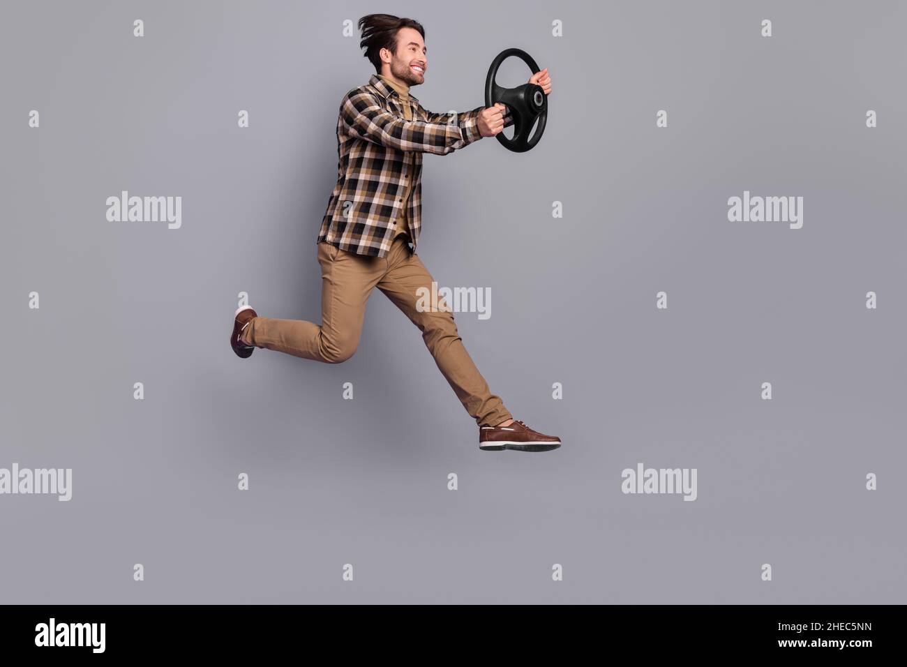 Photo of impressed funny man wear plaid shirt jumping high driving car