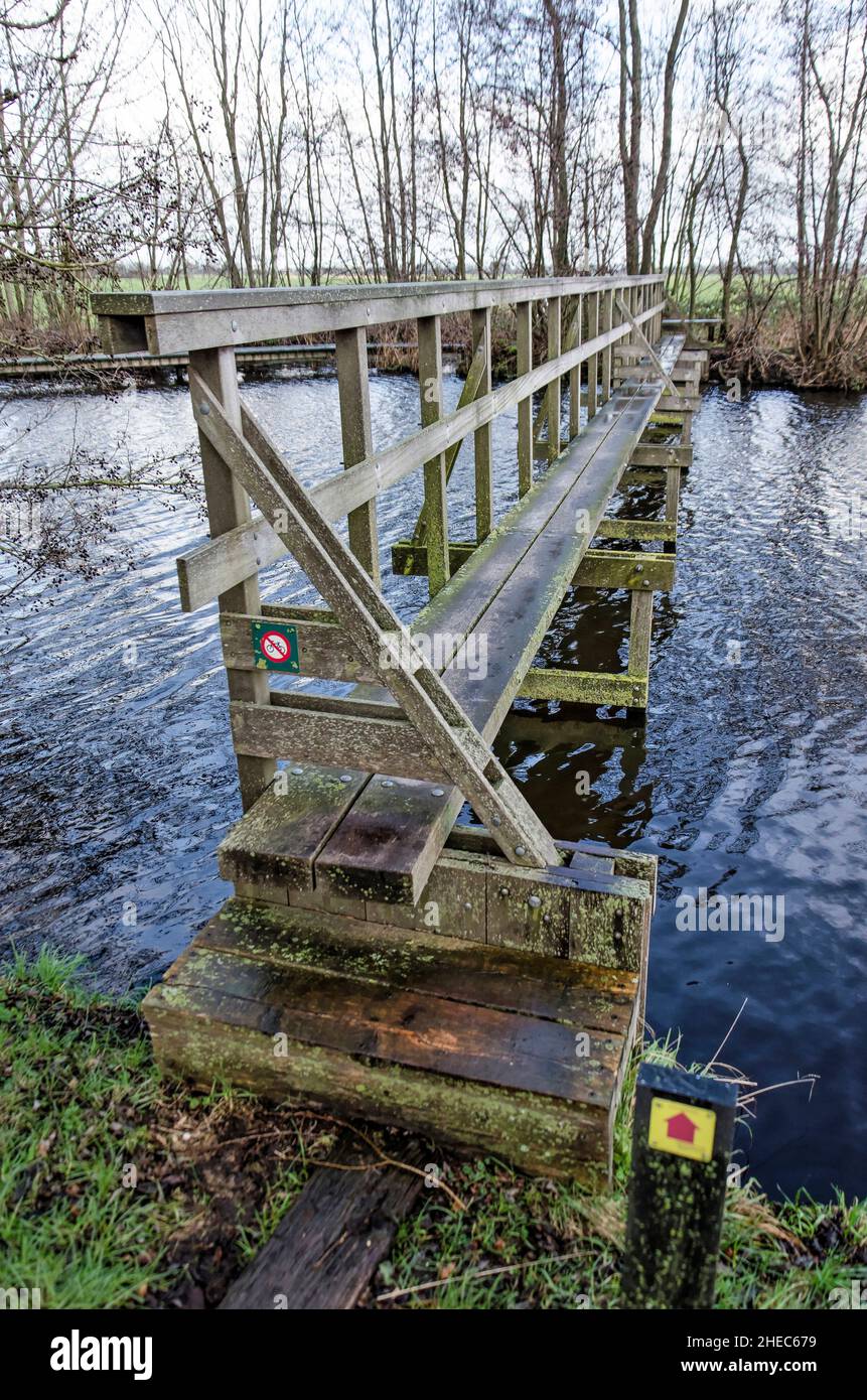 Narrow wooden bridge across a canal connecting two hiking trails in Krimpenerwaard polder in the Netherlands Stock Photo