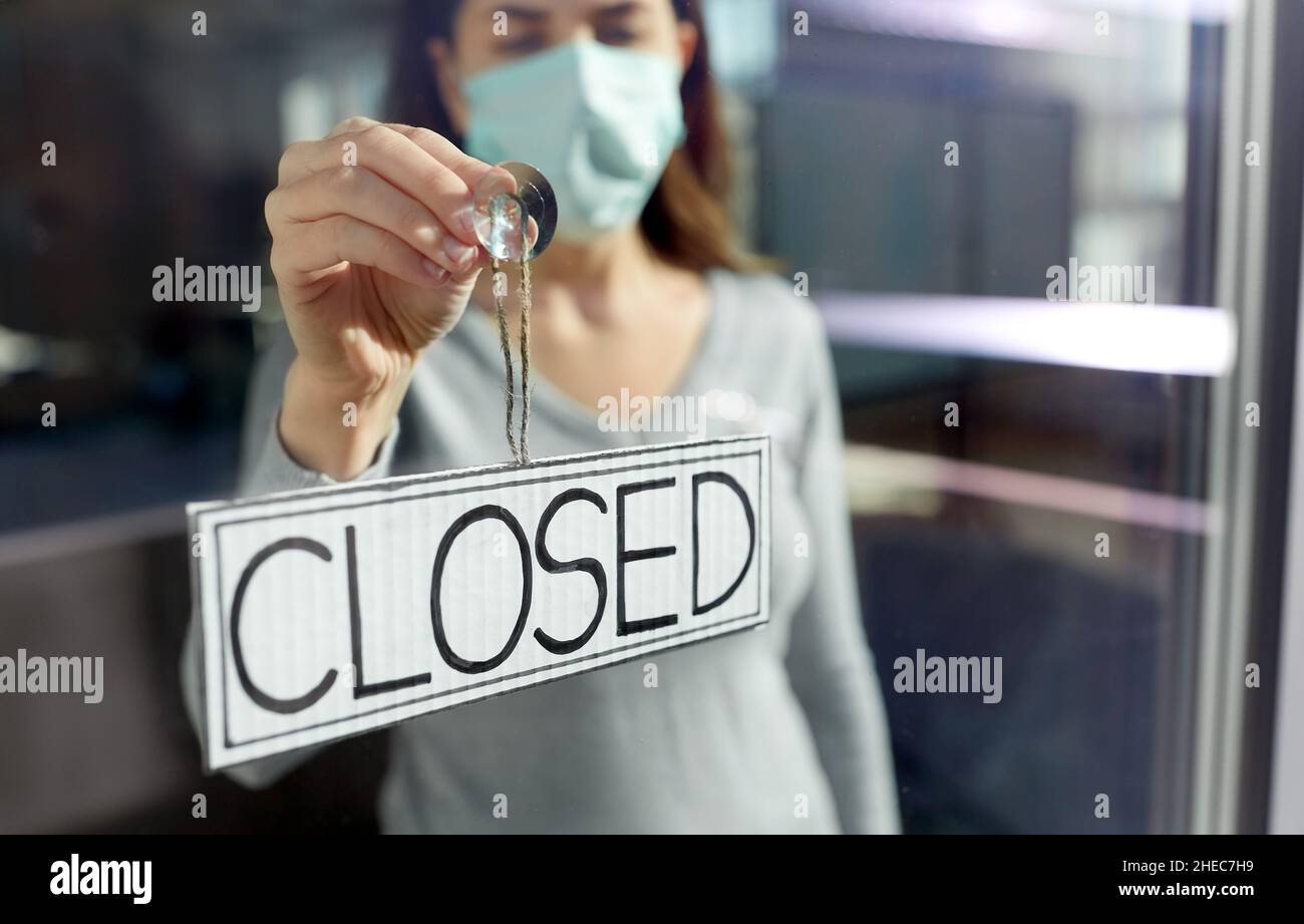 woman in mask hanging banner closed on door Stock Photo