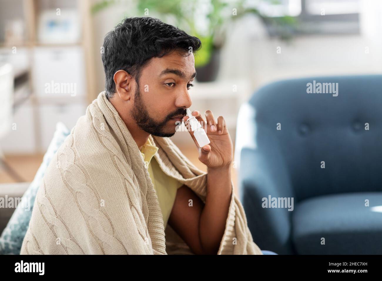 sick indian man using nasal spray at home Stock Photo