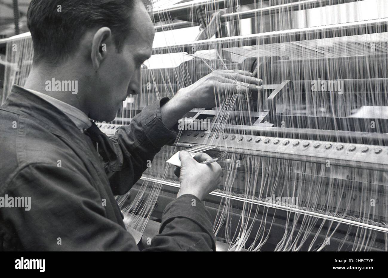 1940s, historical, a male technican at loom at a silk factory, checking the quality of the thread, South Wales, UK. Stock Photo