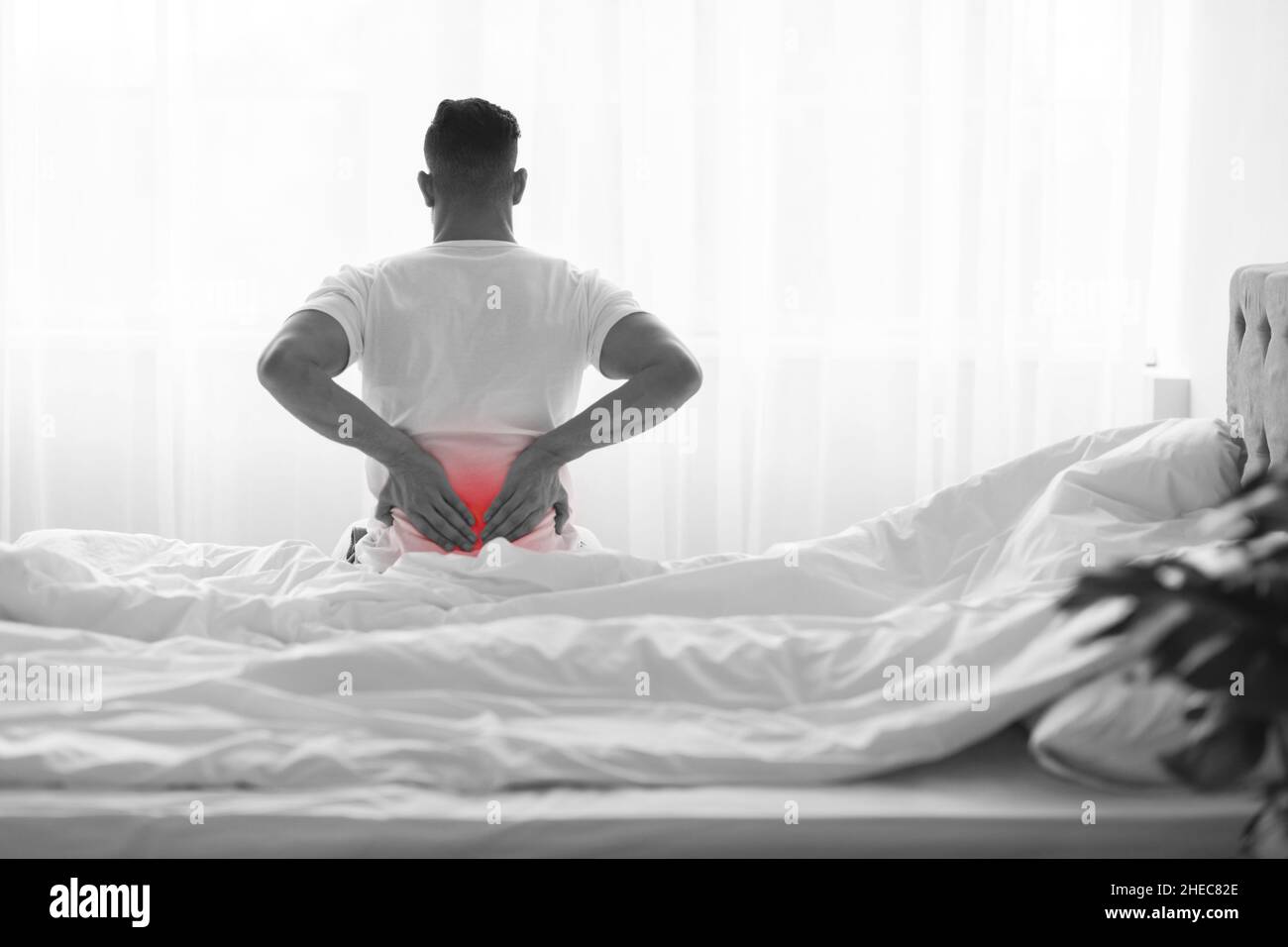 Unrecognizable Man Suffering Lower Back Pain While Sitting On Bed At