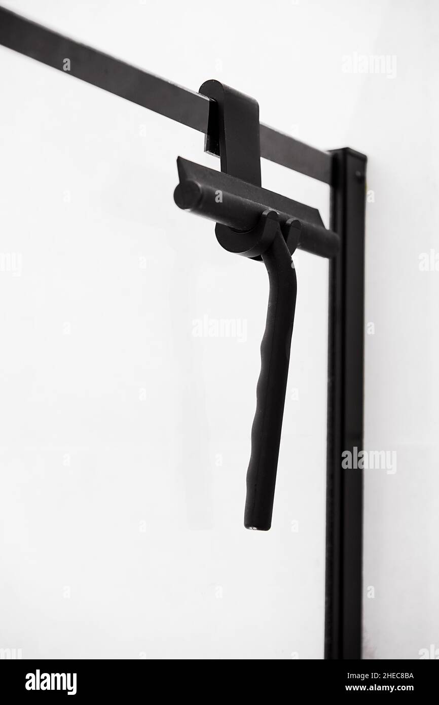 window glass squeegee. Window cleaning black brush is appendant on shower glass. Stock Photo