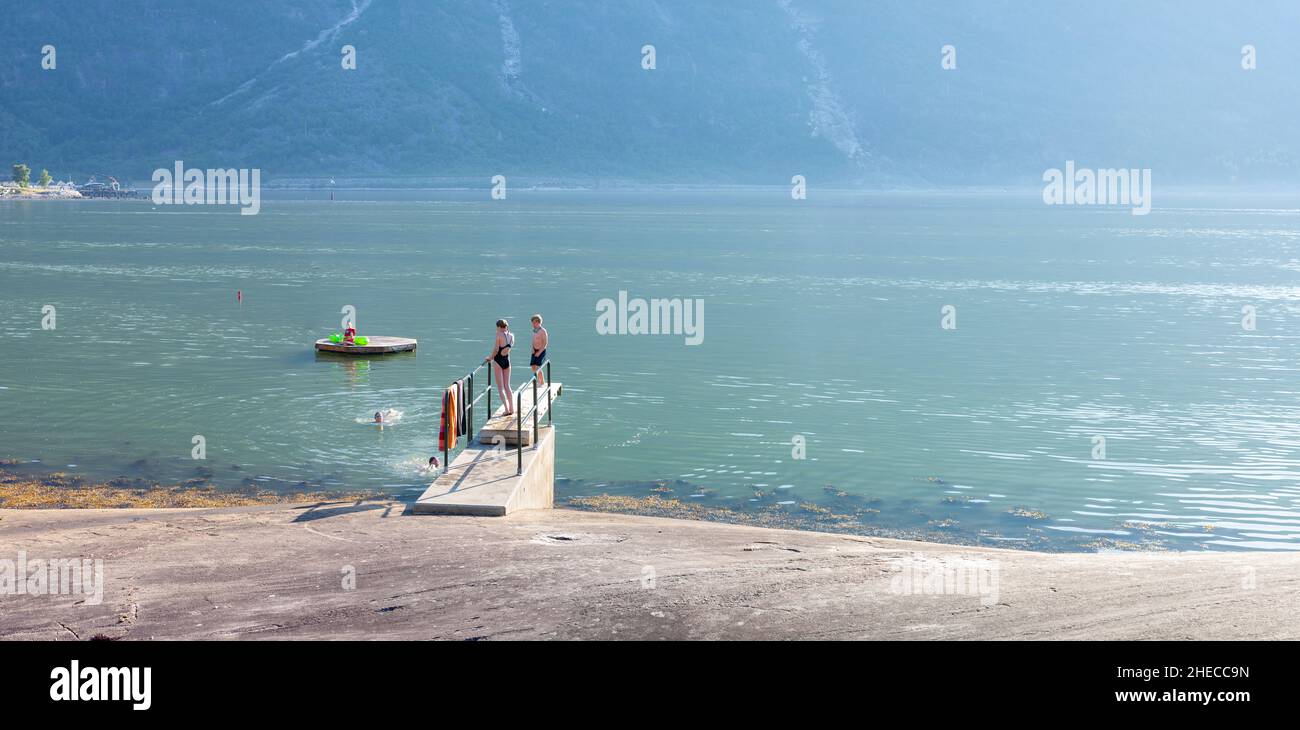 Kids having fun, jumping into cold fjord water, Eidfjord, Norway Stock Photo
