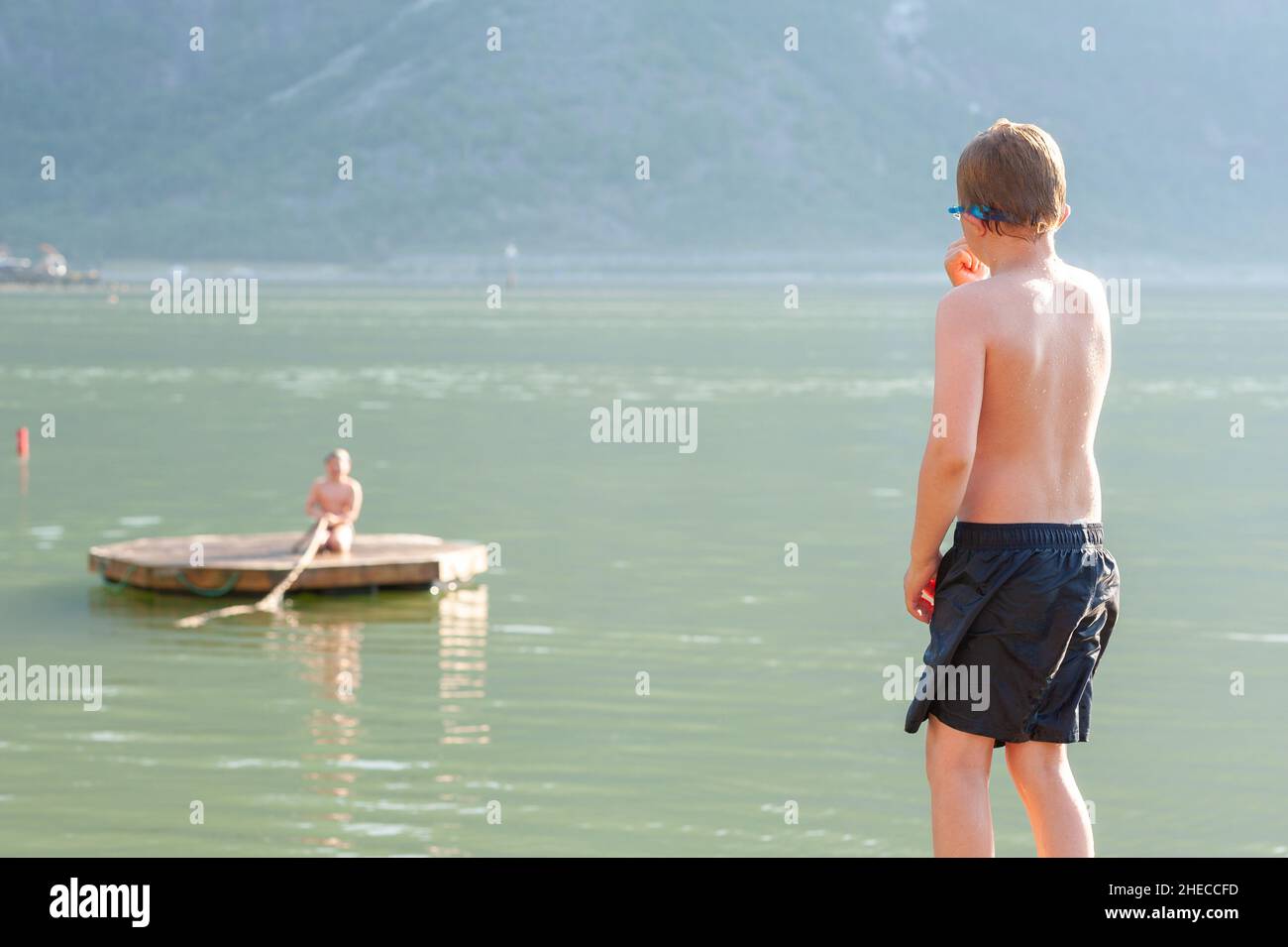 Kids having fun, jumping into cold fjord water, Eidfjord, Norway Stock Photo