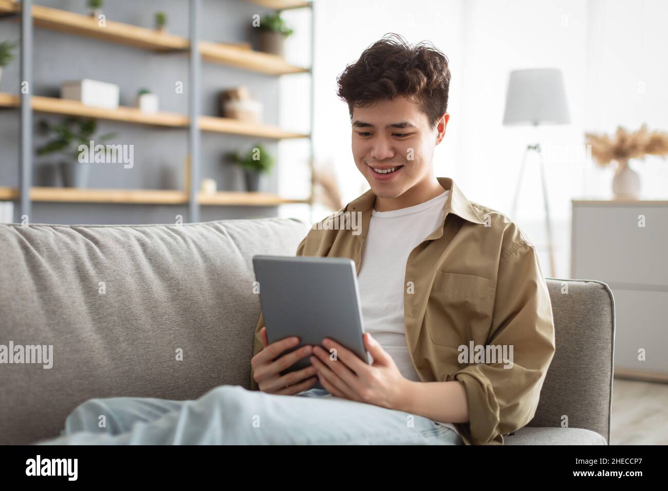 Smiling asian man using digital tablet at home Stock Photo