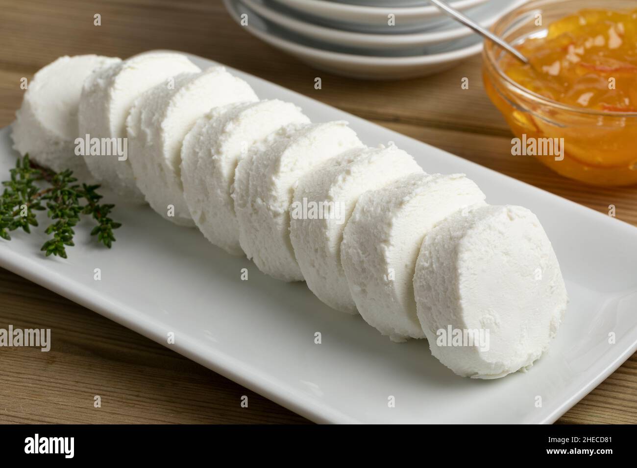 Row of white soft small goat cheese on a plate for a snack with sweet marmalade for topping in the background Stock Photo