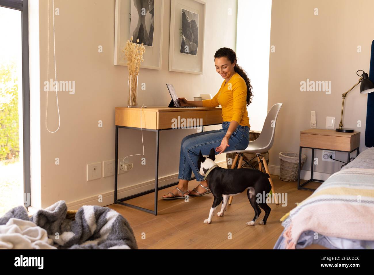 Caucasian woman playing with her dog while using digital tablet at home Stock Photo