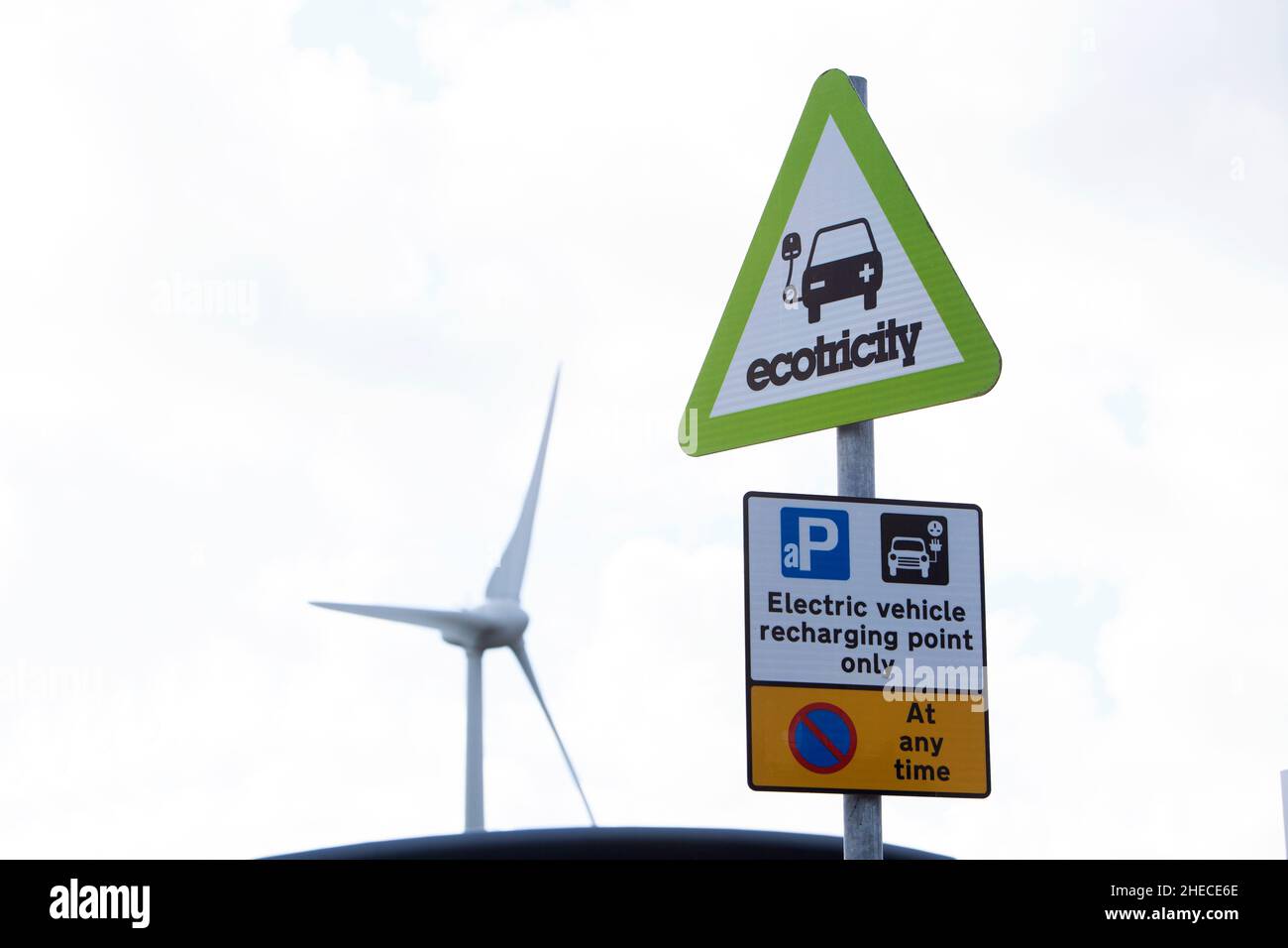 A sign denoting a charging point for electric vehicles situated near a wind turbine Stock Photo