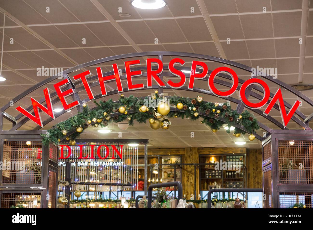 Sign / signage at The Red Lion Wetherspoon / Wetherspoons Pub / restaurant / Public House, at London Gatwick airport North Terminal, Crawley. UK. Christmas Xmas decorations are visible. (128) Stock Photo