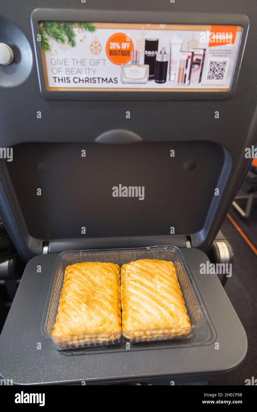 Cheese and onion pasty, pasties / filling food with plenty of energy, on a seat tray table, on an Airbus A320 or A319 plane / airplane aeroplane. Part of a packed lunch for a passenger who took food snack on board the EasyJet flight for part of a self catering meal. (128) Stock Photo