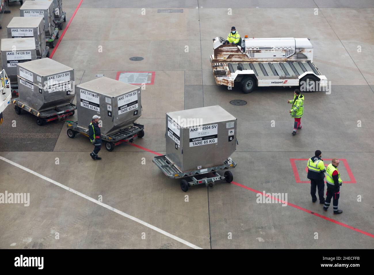 Ground crew or baggage handlers with Airport Ground Support Equipment wait to load cargo freight containers onto a plane / airplane / aeroplane at Geneva airport, Switzerland. (128) Stock Photo