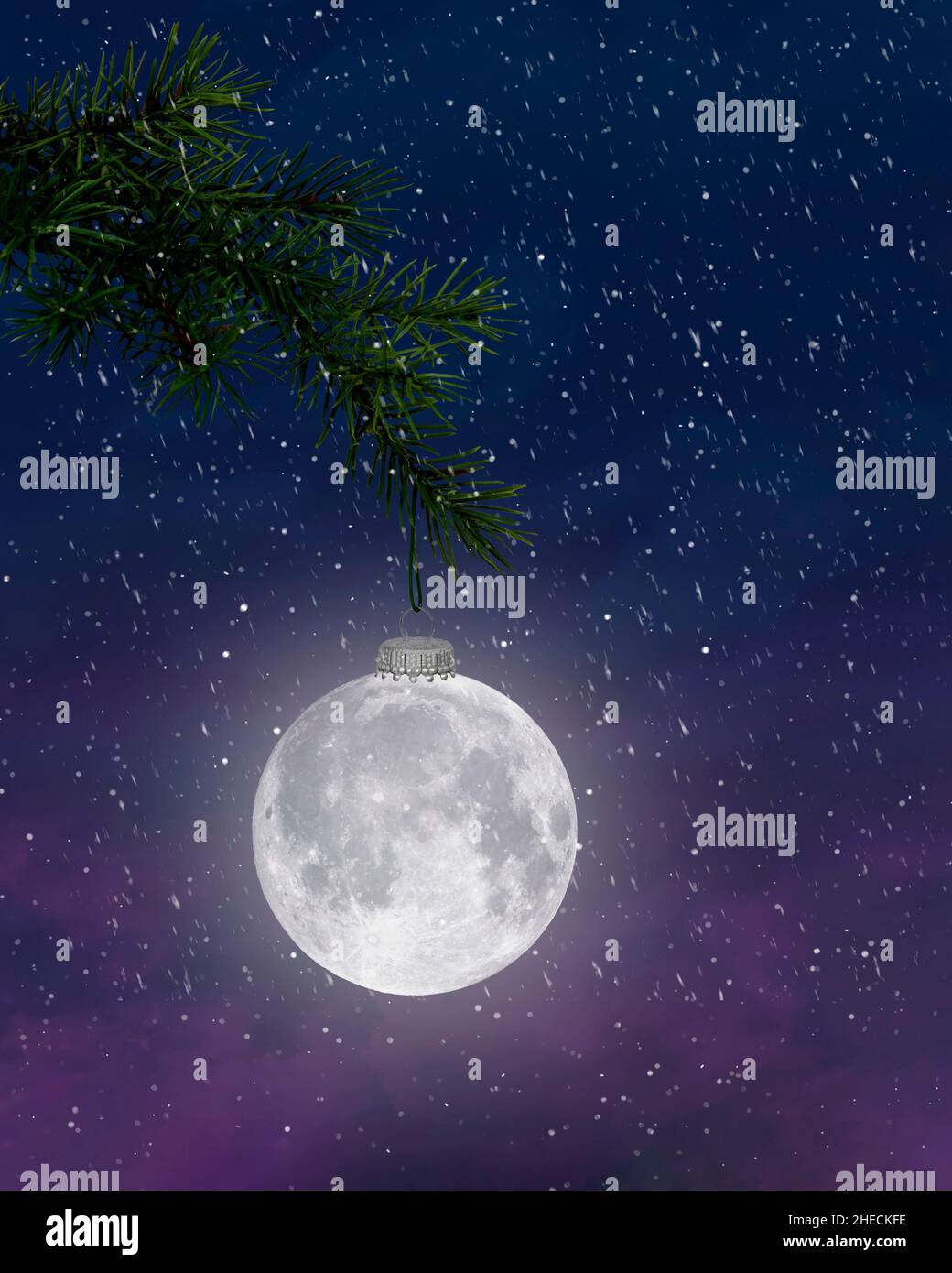 Full moon holiday ornament hanging from pine bough in snowflakes Stock Photo