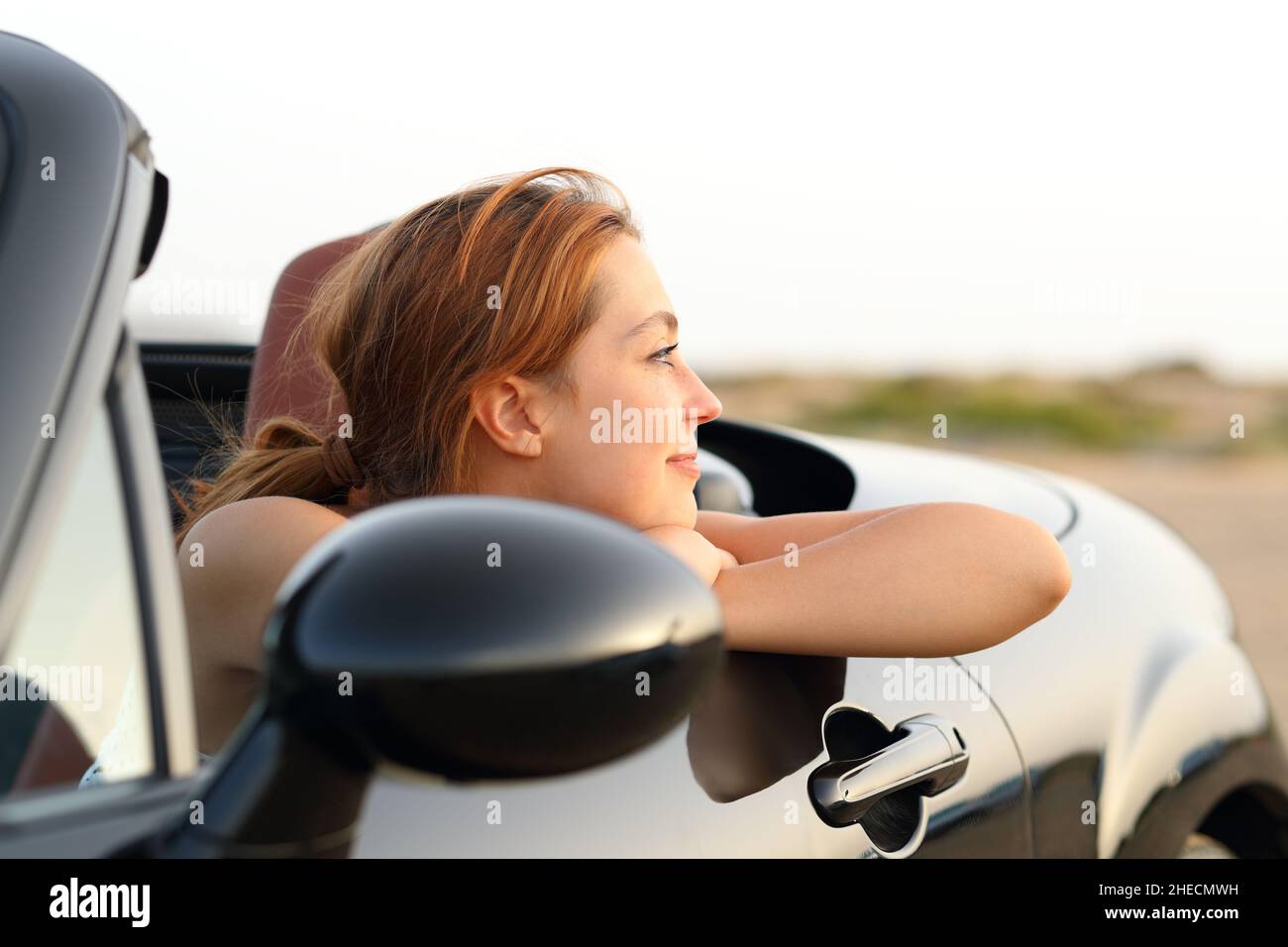 Satisfied woman contemplating views resting from a convertible car Stock Photo