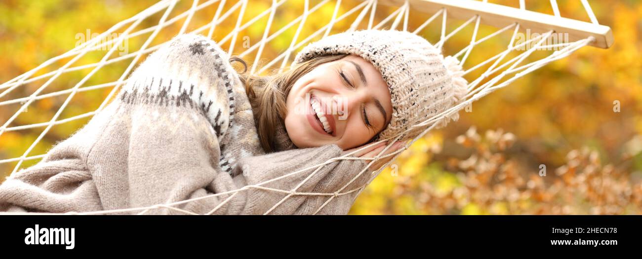 Happy woman smiling lying on hammock in autumn season in a forest Stock Photo