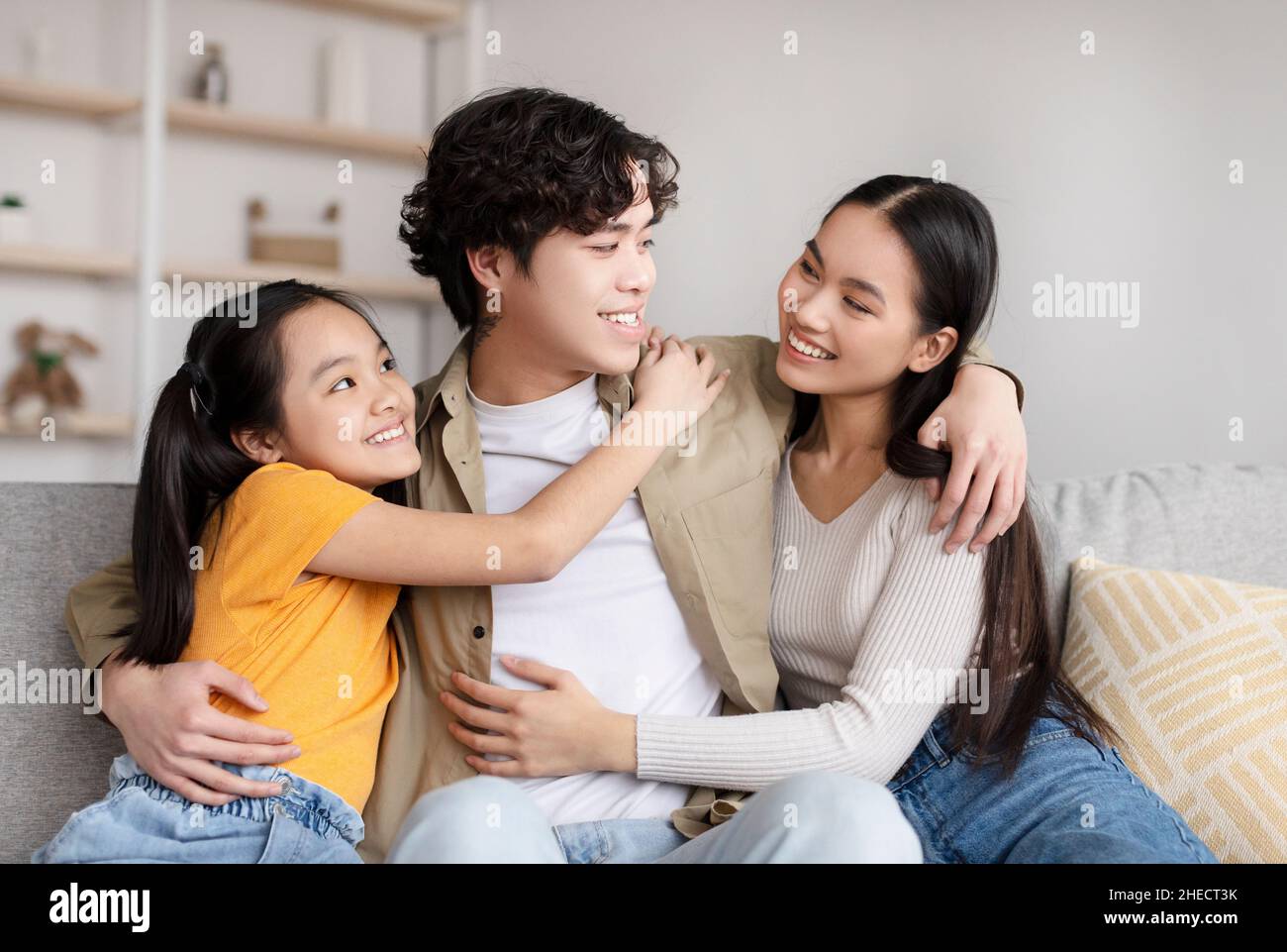 Satisfied young korean family hugging and enjoying rest, free time on weekend Stock Photo