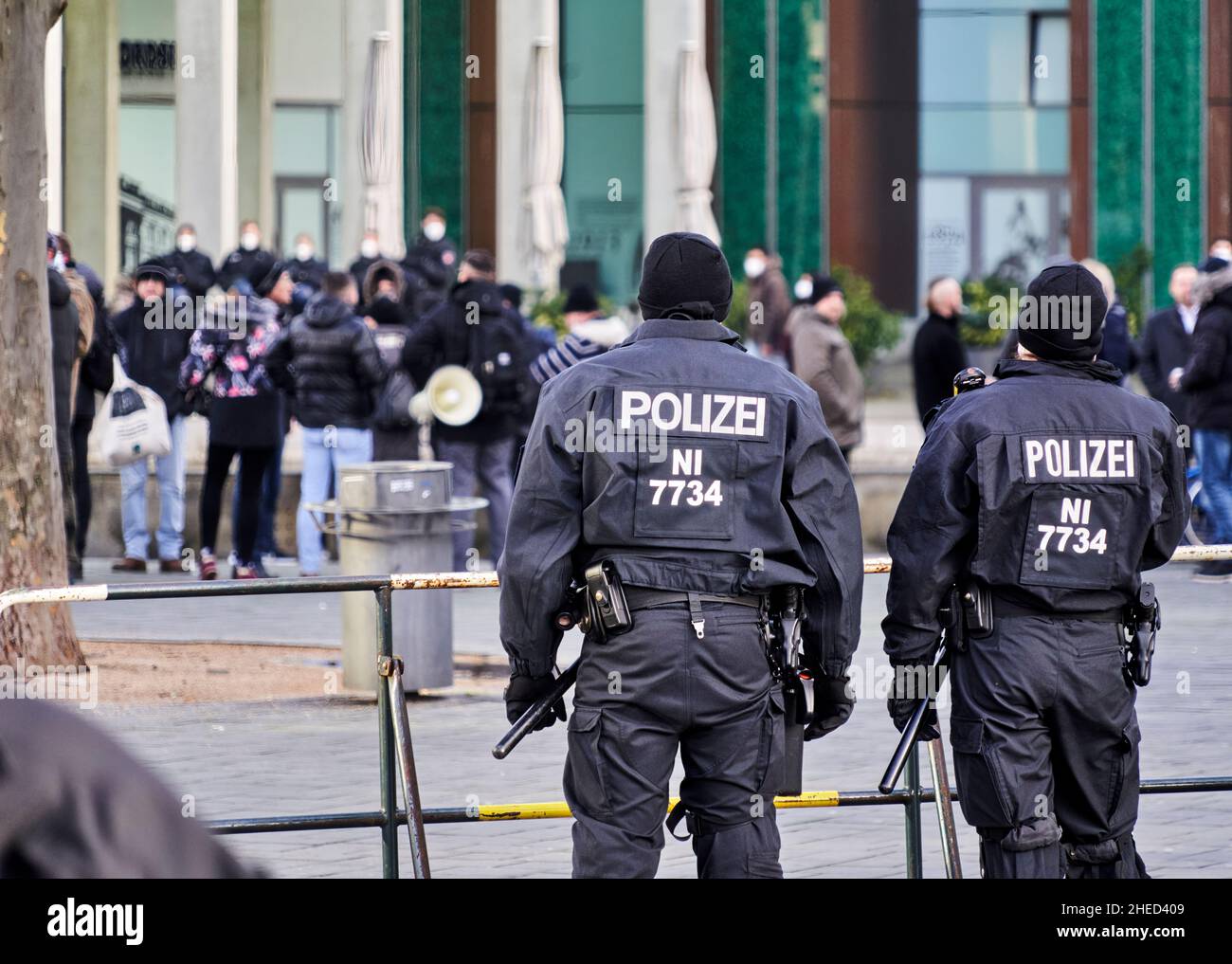 Braunschweig, Germany, January 8, 2022: Back view of black uniformed police officers at a barrier separating disputing parties at a demonstration Stock Photo
