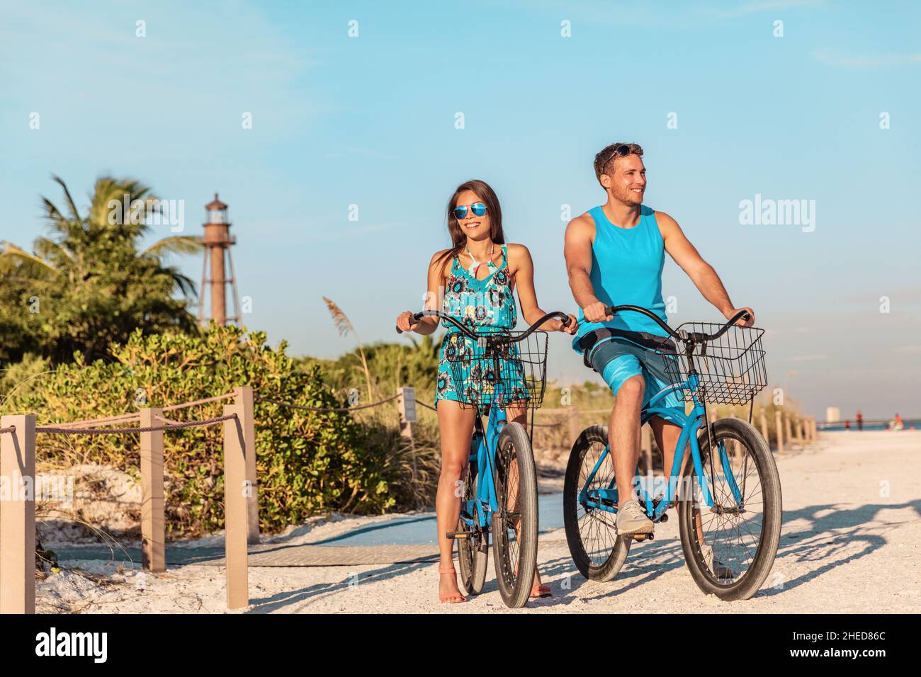Biking activity couple tourists having fun doing outdoor sport on Florida beach vacation with rental bikes on Sanibel Island by the Lighthouse. woman Stock Photo