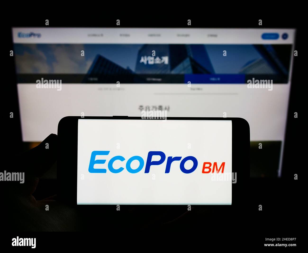 Person holding smartphone with logo of South Korean company Ecopro BM Co. Ltd. on screen in front of website. Focus on phone display. Stock Photo