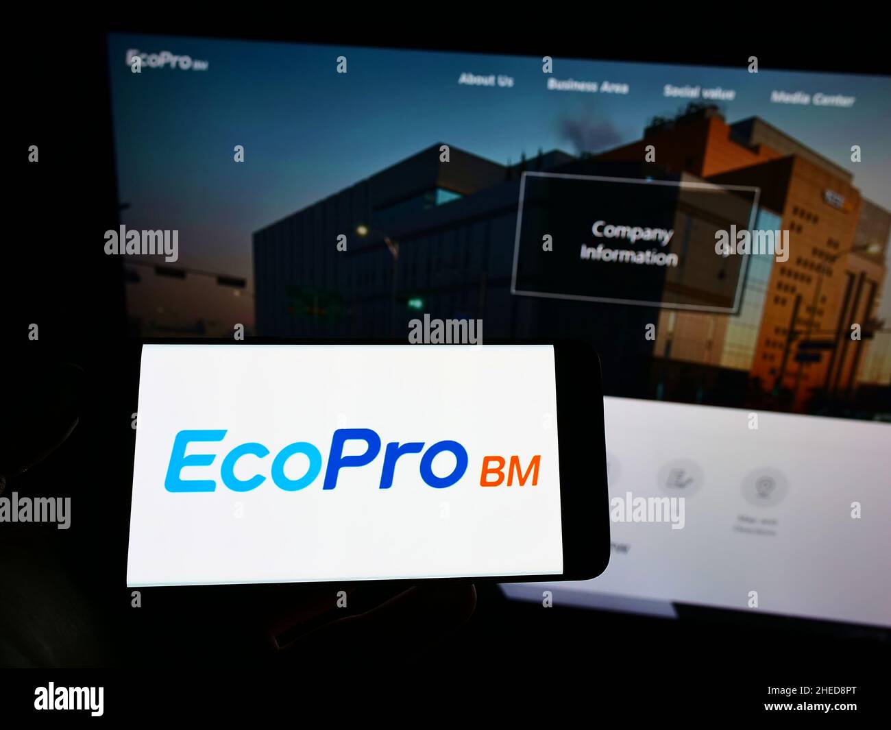 Person holding cellphone with logo of South Korean company Ecopro BM Co. Ltd. on screen in front of business webpage. Focus on phone display. Stock Photo