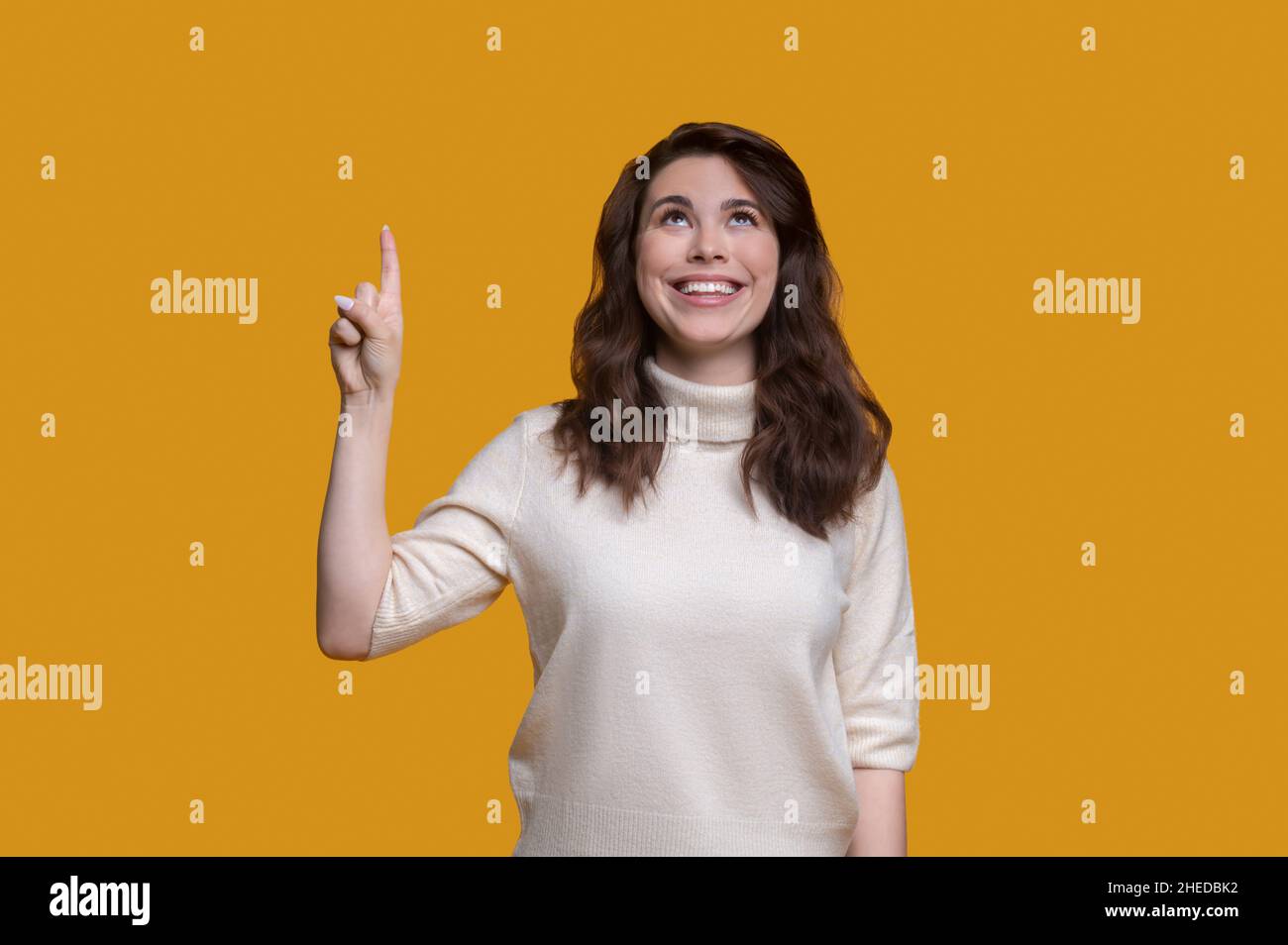 Joyous lady with the lifted forefinger looking upwards Stock Photo
